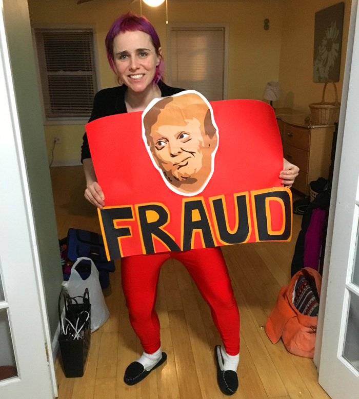 FRAUD erica holding a sign with the face of Trmp and the word FRAUD