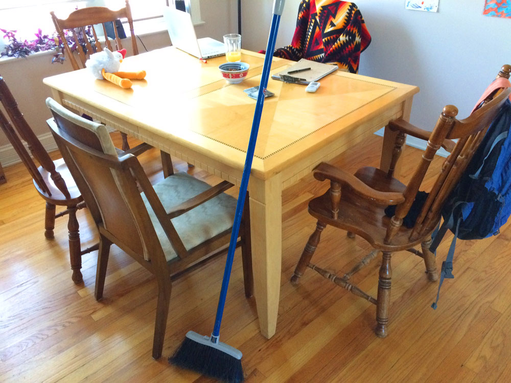 broom broom leaning against a kitchen table